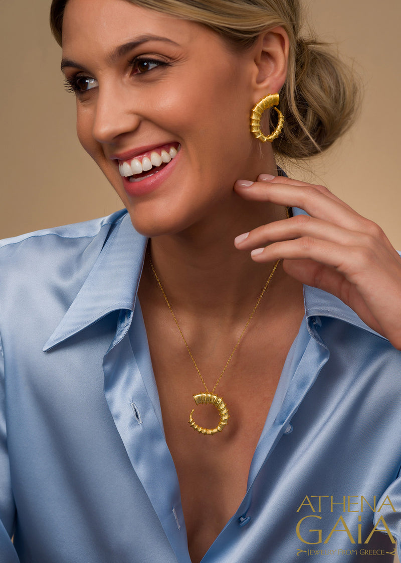 smiling woman wearing 18k gold hoop earrings and necklace