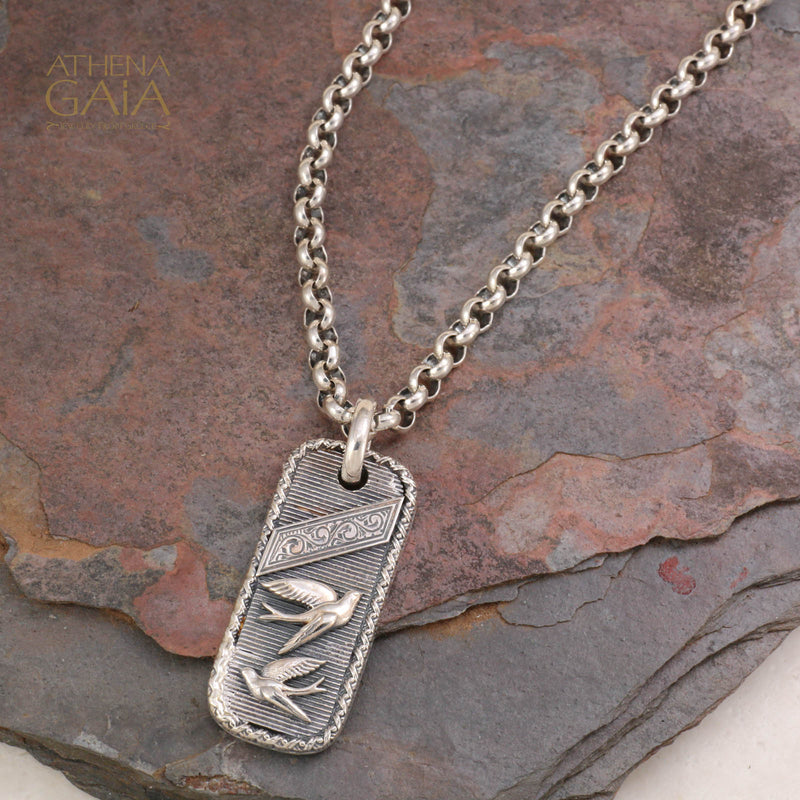 Silver pendant necklace with engraved flying birds on textured background, crafted in Greece.