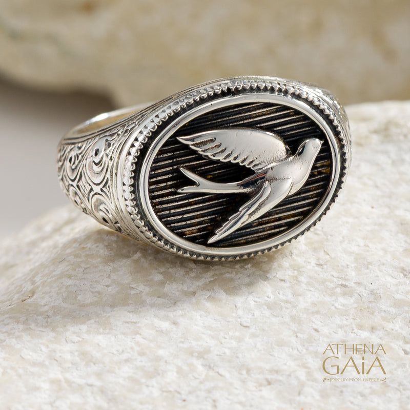 925 Silver oval ring with single swallow bird design on a stone surface, featuring the brand 'Athena Gaia'.
