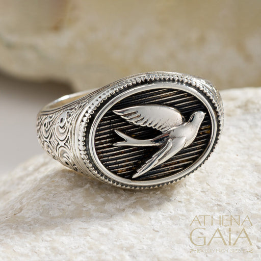 925 Silver oval ring with single swallow bird design on a stone surface, featuring the brand 'Athena Gaia'.
