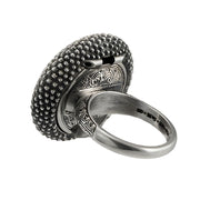 A sterling silver and gold ring featuring a textured surface with dolphin shell designs and a central green gemstone.