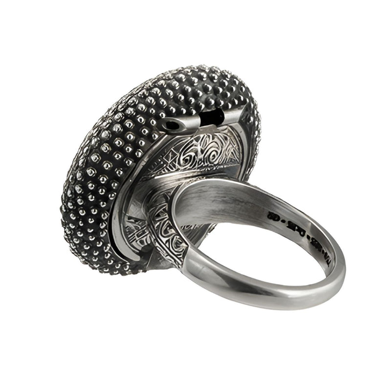 A sterling silver and gold ring featuring a textured surface with dolphin shell designs and a central green gemstone.