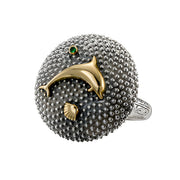 A sterling silver and gold ring featuring a textured surface with dolphin shell designs and a central green gemstone.