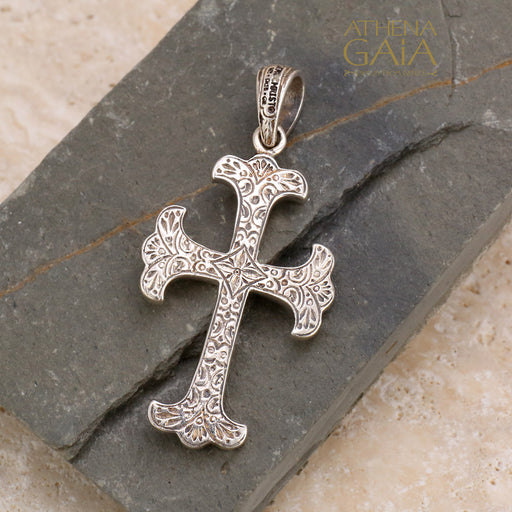 Silver Orthodox cross pendant on a stone surface with Gerochristo certification stamp.