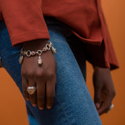 Hand wearing a bracelet with charms against an orange background