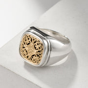 Silver ring with gold intricate design on a light gray background