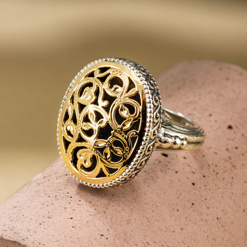 A medium sized oval filigree ring with floral patterns on the face.