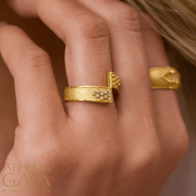 A model wearing diamond and gold earrings, and two rings with diamonds