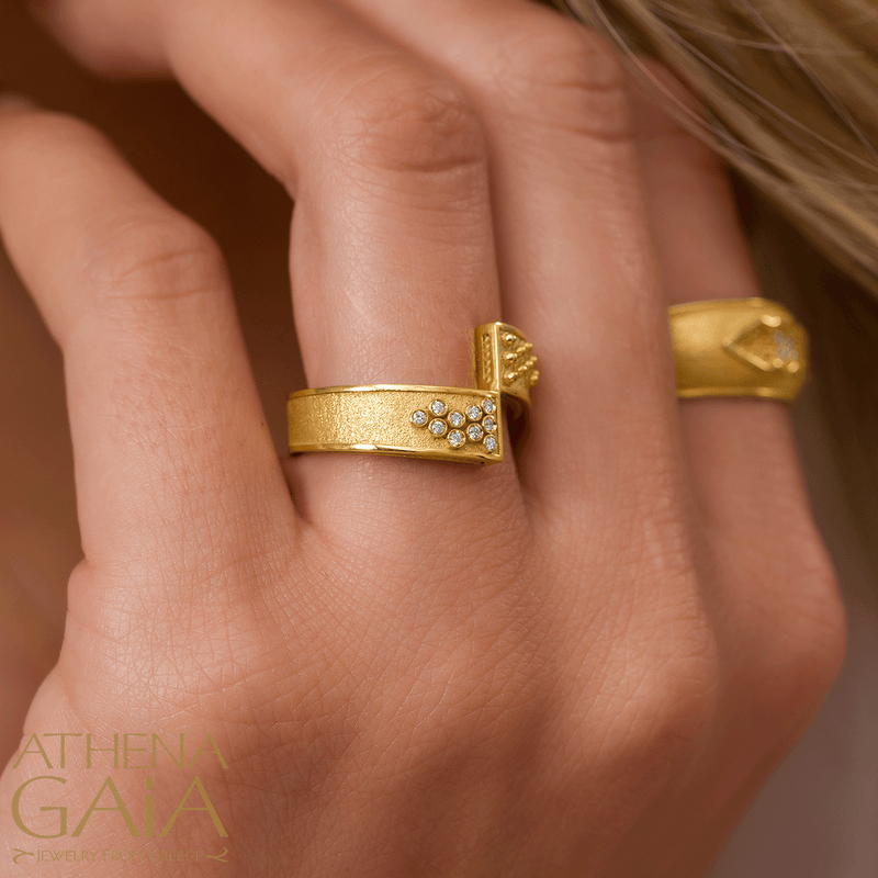 A model wearing diamond and gold earrings, and two rings with diamonds