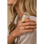 A gold ring with multiple bands, featuring diamonds set in a Byzantine style design on a person's hand.
