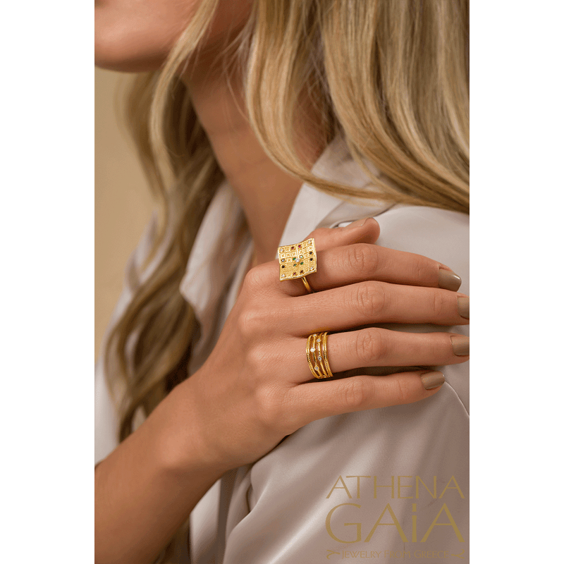 A gold ring with multiple bands, featuring diamonds set in a Byzantine style design on a person's hand.