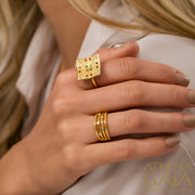 A woman wearing a gold ring with a colorful, intricate design, part of the Royal Heritage collection.