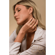 A model wearing diamond and gold earrings, and two rings with diamonds