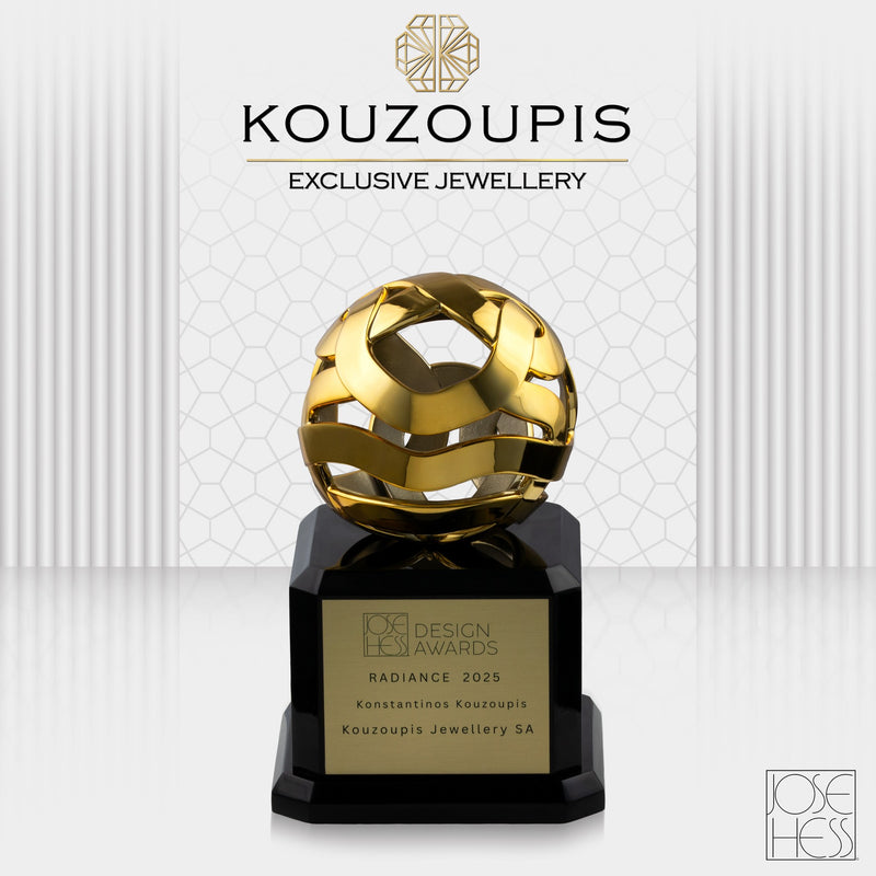 Gold jewelry award on a black base with 'Kouzoupis Exclusive Jewellery' branding.