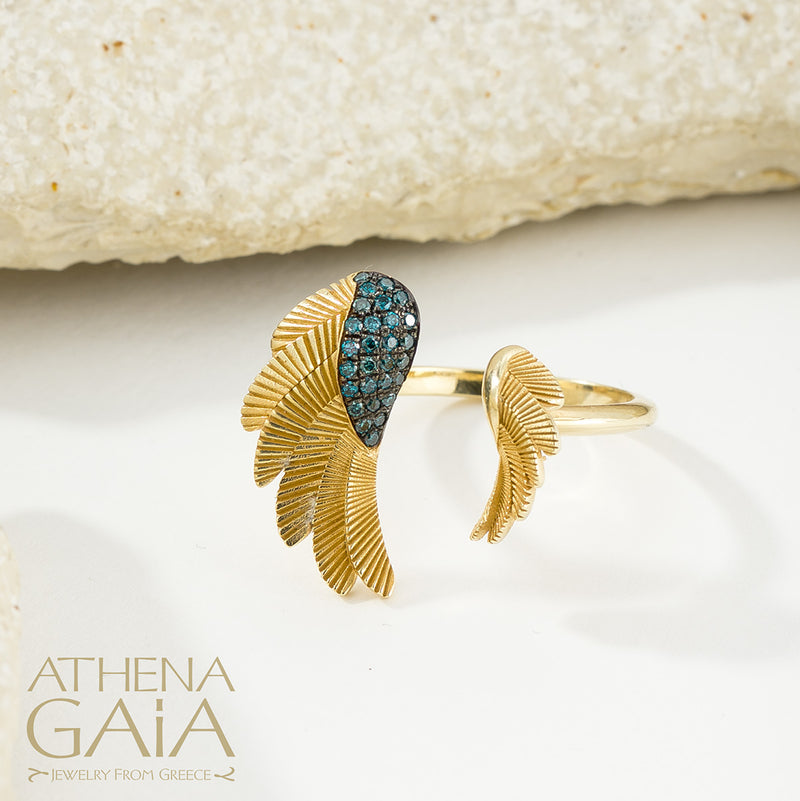 A gold ring with a feathered wing design set with blue gemstones, displayed on a white surface.