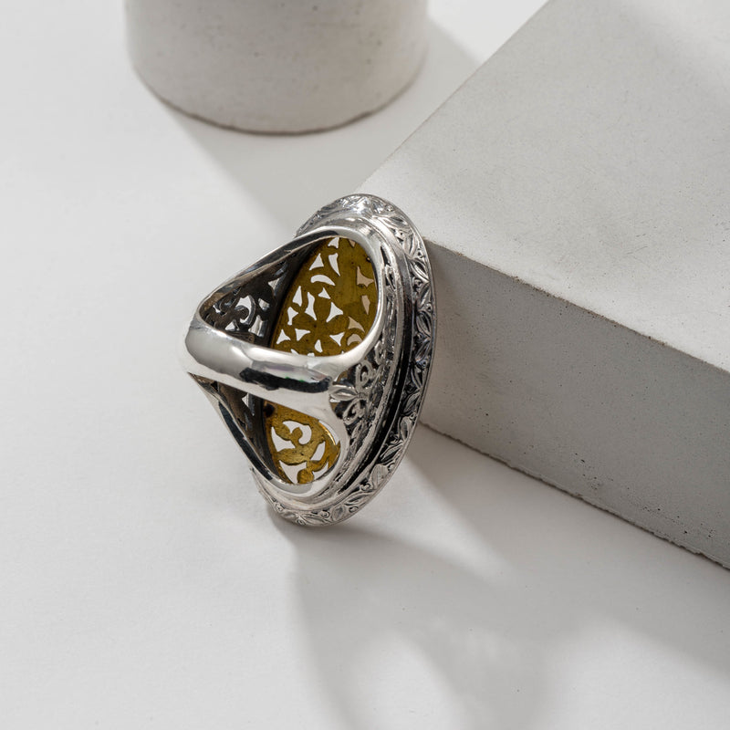 A large oval filigree ring with floral patterns on the face and shank