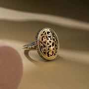 A medium sized oval filigree ring with floral patterns on the face.