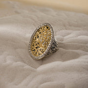 A large oval filigree ring with floral patterns on the face and shank