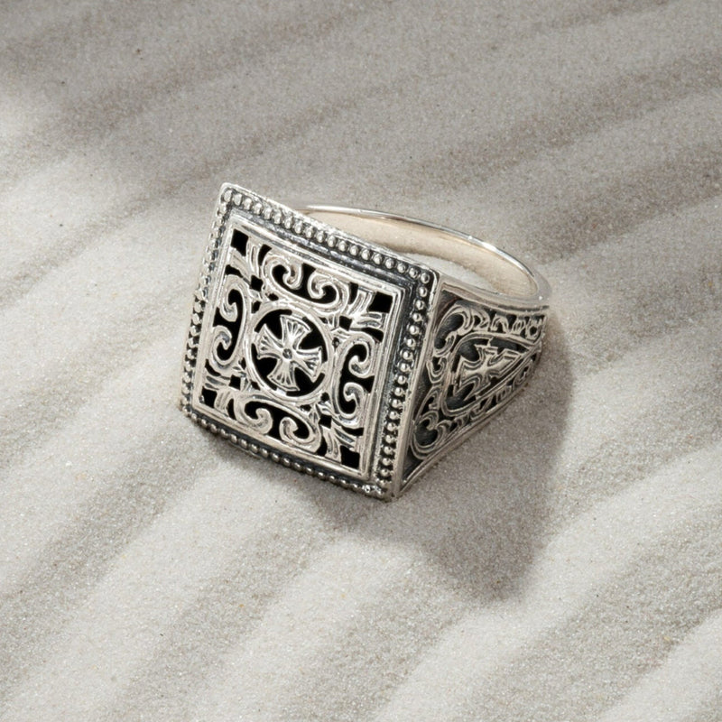 Silver ring with intricate design on sand