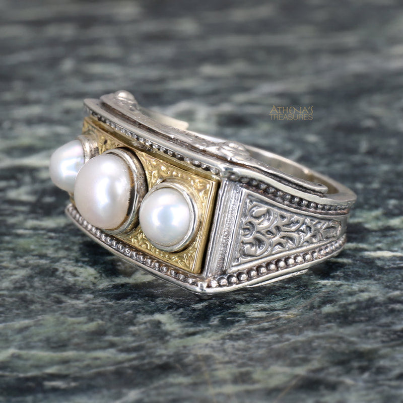 A ring featuring three white pearls set in a sterling silver and solid 18k gold band with intricate embossing.
