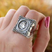 A unisex sterling silver signet ring featuring a profile of Alexander the Great within a decorative frame, displayed on a rock.