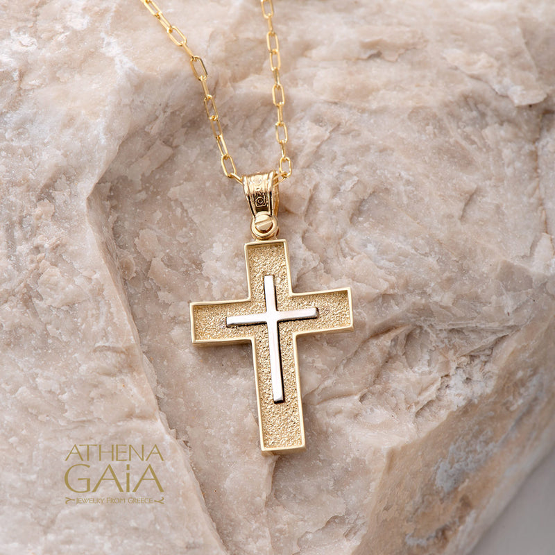14k gold Orthodox Baptism cross necklace shown on a beige rock