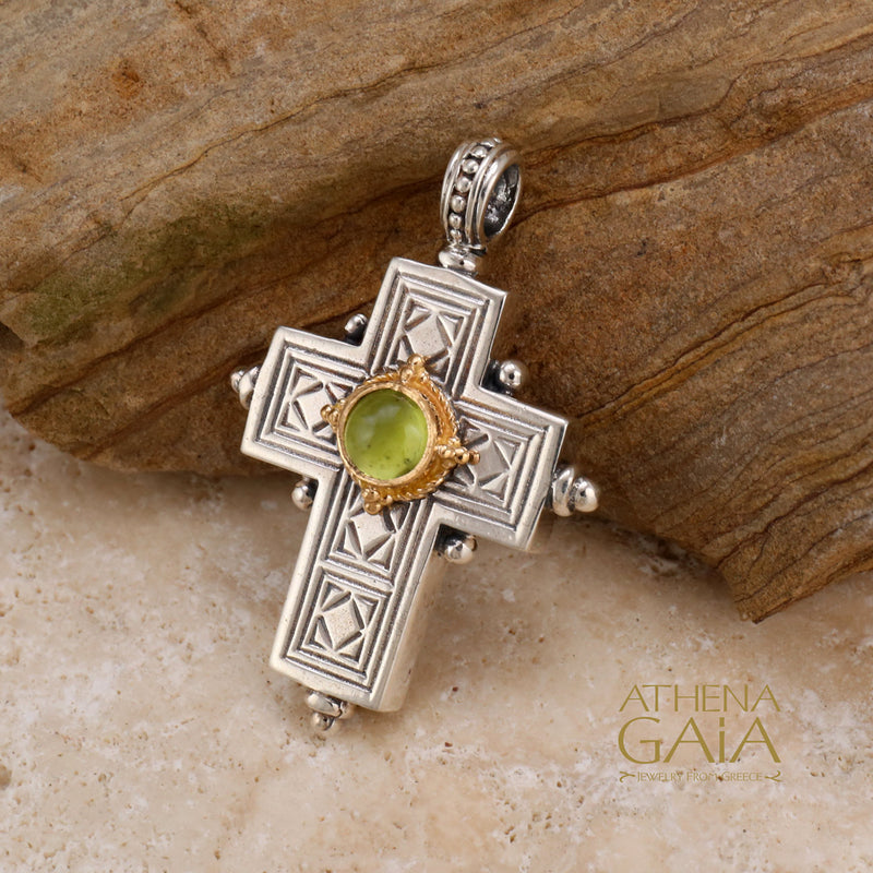 Silver and gold cross pendant featuring geometric engravings and a vibrant green gemstone centerpiece, symbolizing faith and renewal.
