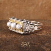 A ring featuring three white pearls set in a sterling silver and solid 18k gold band with intricate embossing.