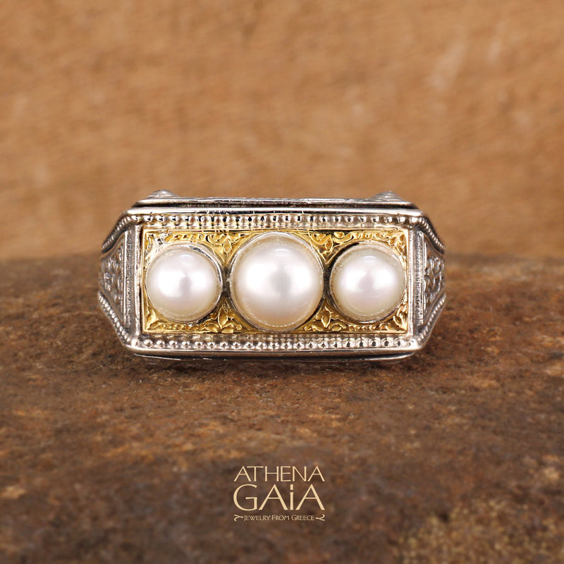 A ring featuring three white pearls set in a sterling silver and solid 18k gold band with intricate embossing.