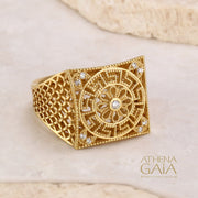 A gold square ring with intricate filigree details and diamonds on a stone with the Athena Gaia Jewelry logo visible.