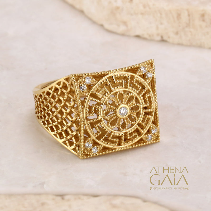 A gold square ring with intricate filigree details and diamonds on a stone with the Athena Gaia Jewelry logo visible.