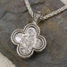 Silver clover shaped pendant featuring a detailed Byzantine style icon on a woven chain necklace.