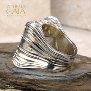 A unisex sterling silver signet ring featuring a profile of Alexander the Great within a decorative frame, displayed on a rock.