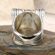 A unisex sterling silver signet ring featuring a profile of Alexander the Great within a decorative frame, displayed on a rock.