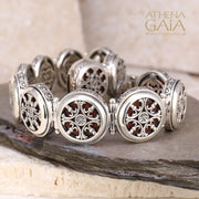 Silver bracelet with circular filigree links and intricate openwork design, displayed on stone slabs.