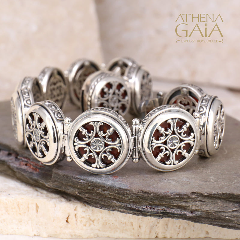 Silver bracelet with circular filigree links and intricate openwork design, displayed on stone slabs.