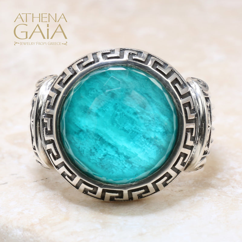 A silver ring with a blue stone featuring Ionic column designs and a Meander Greek key pattern.