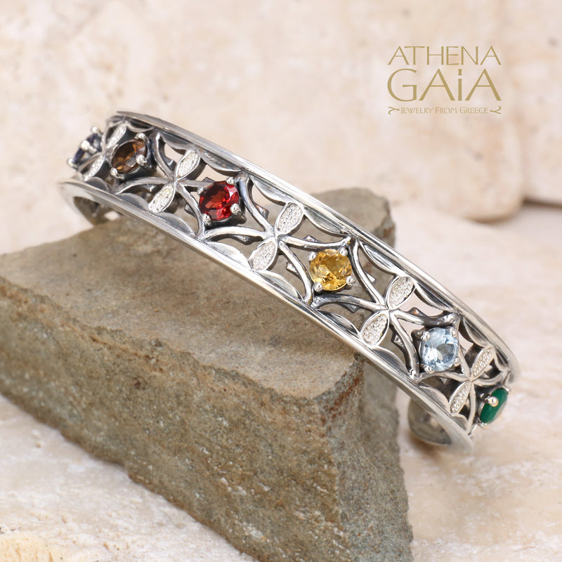 Silver bracelet with gemstones on a stone surface, featuring the Athena Gaia brand.