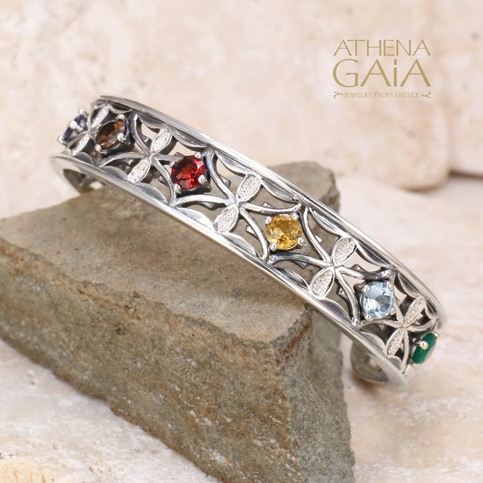 Silver bracelet with gemstones on a stone surface, featuring the Athena Gaia brand.