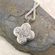 Silver clover shaped pendant featuring a detailed Byzantine style icon on a woven chain necklace.