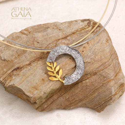 A radiant gold-plated olive branch rests on a textured silver crescent, symbolizing peace and harmony