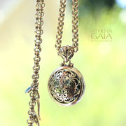 silver rolo chain necklace and pendant with intricate pendant on a blurred green background