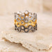 Honeycomb pattern ring in silver and gold tones, displayed on a beige stone with soft lighting.