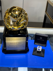 Gold jewelry piece with a black box labeled 'Pandora' on a blue surface.