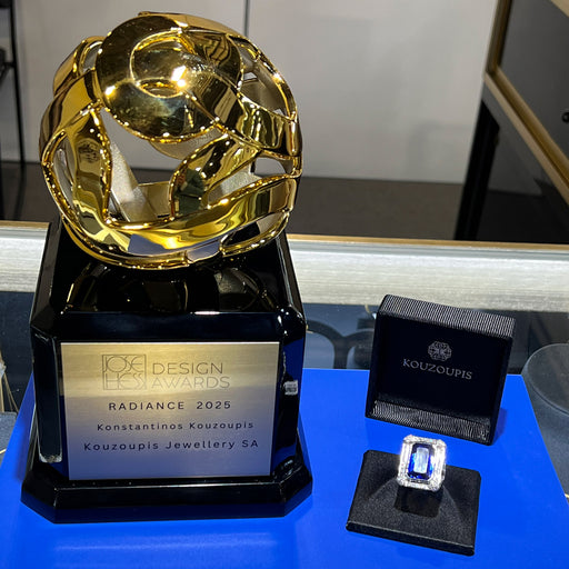 Gold jewelry piece with a black box on a blue surface.