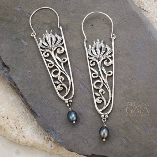Silver filigree earrings with floral design, red gemstone accents, and blue pearl drops.
