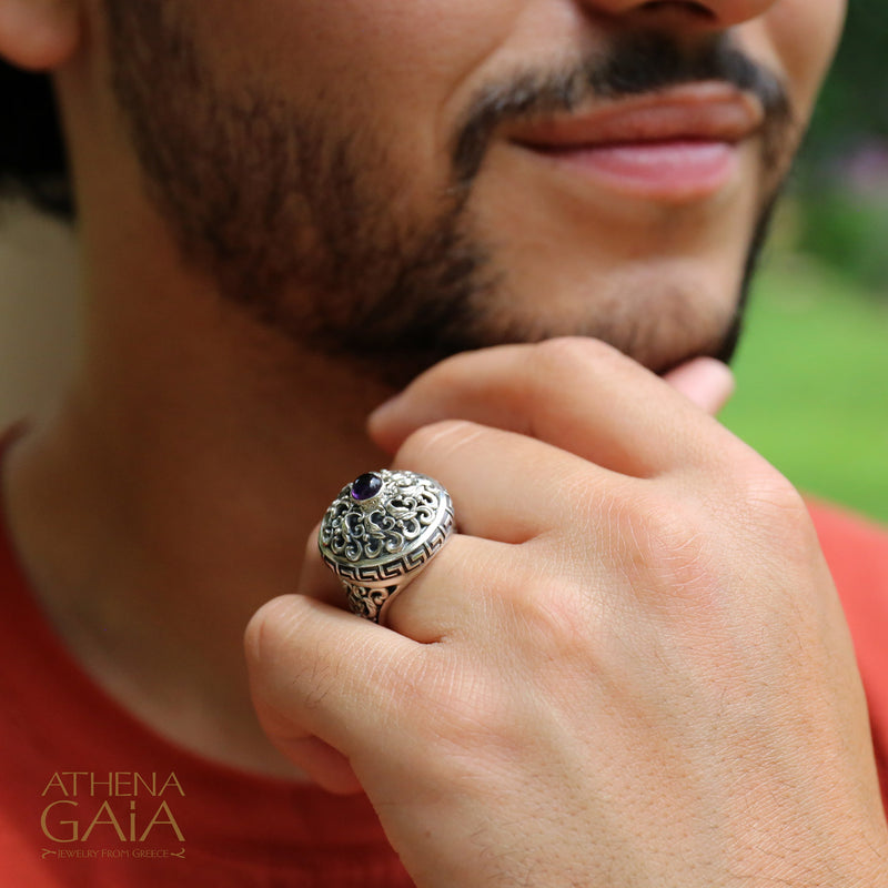 Man wearing a silver ring with intricate design, blurred background
