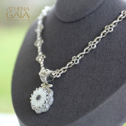 Silver pendant with a carved mother-of-pearl flower on a chain necklace.