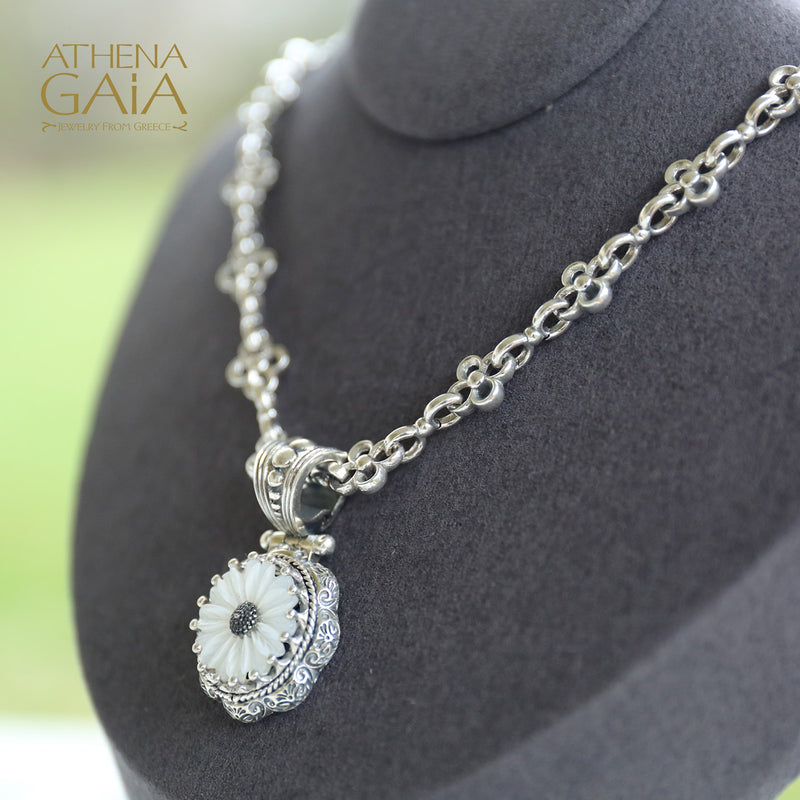 Silver pendant with a carved mother-of-pearl flower on a chain necklace.