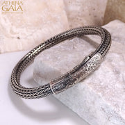 Woven silver bracelet with detailed floral clasp design, handcrafted in Greek artisan style.